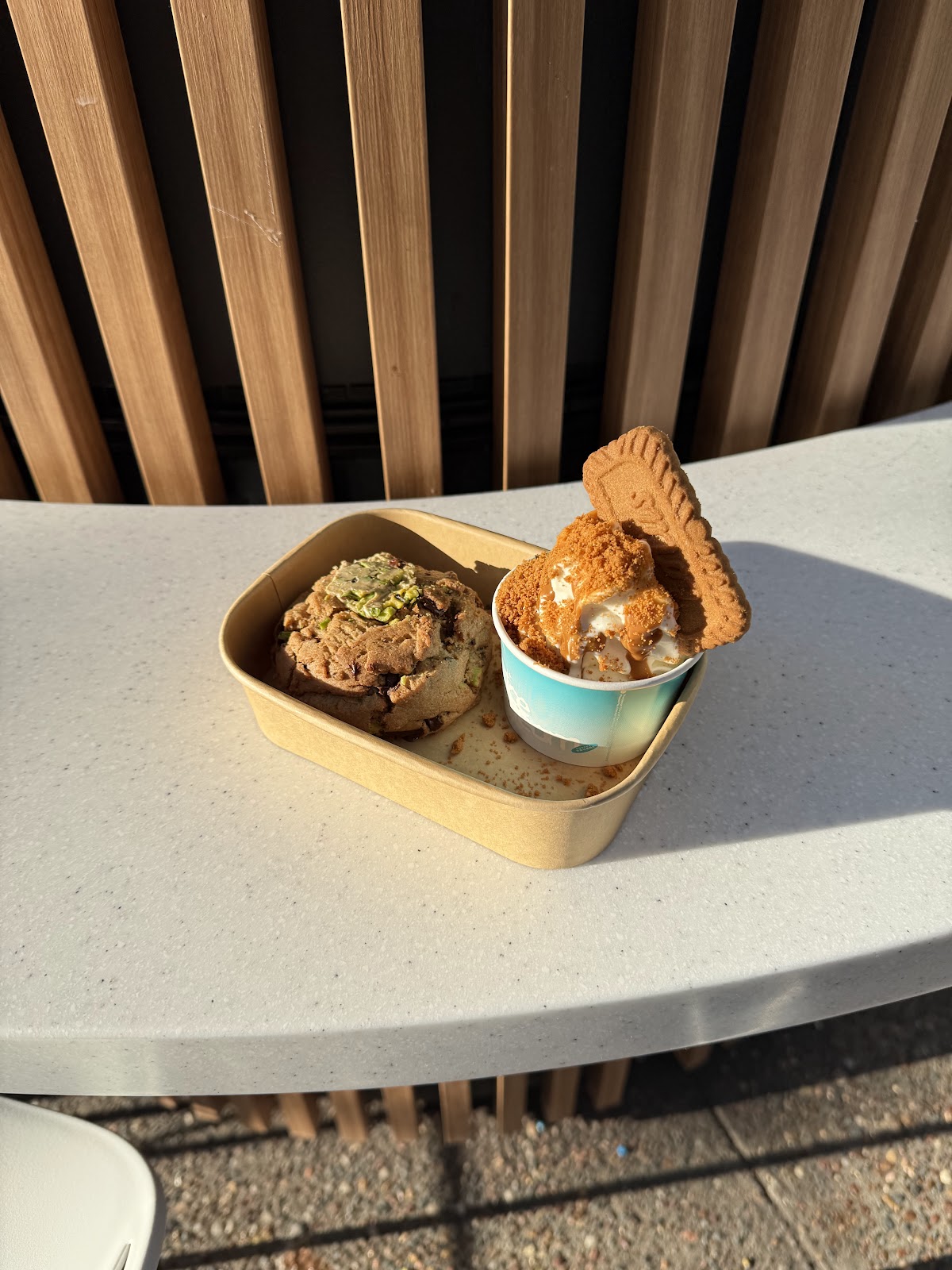 Two soft serve cups with cookie crumb and biscuit toppings on the kiosk bench
